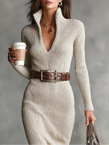 Close-up of a woman's torso in a cream ribbed knit dress, showing the neckline, belt, and handbag