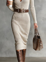 Woman in a cream ribbed knit dress, brown belt, and cowboy boots, holding a coffee cup and handbag