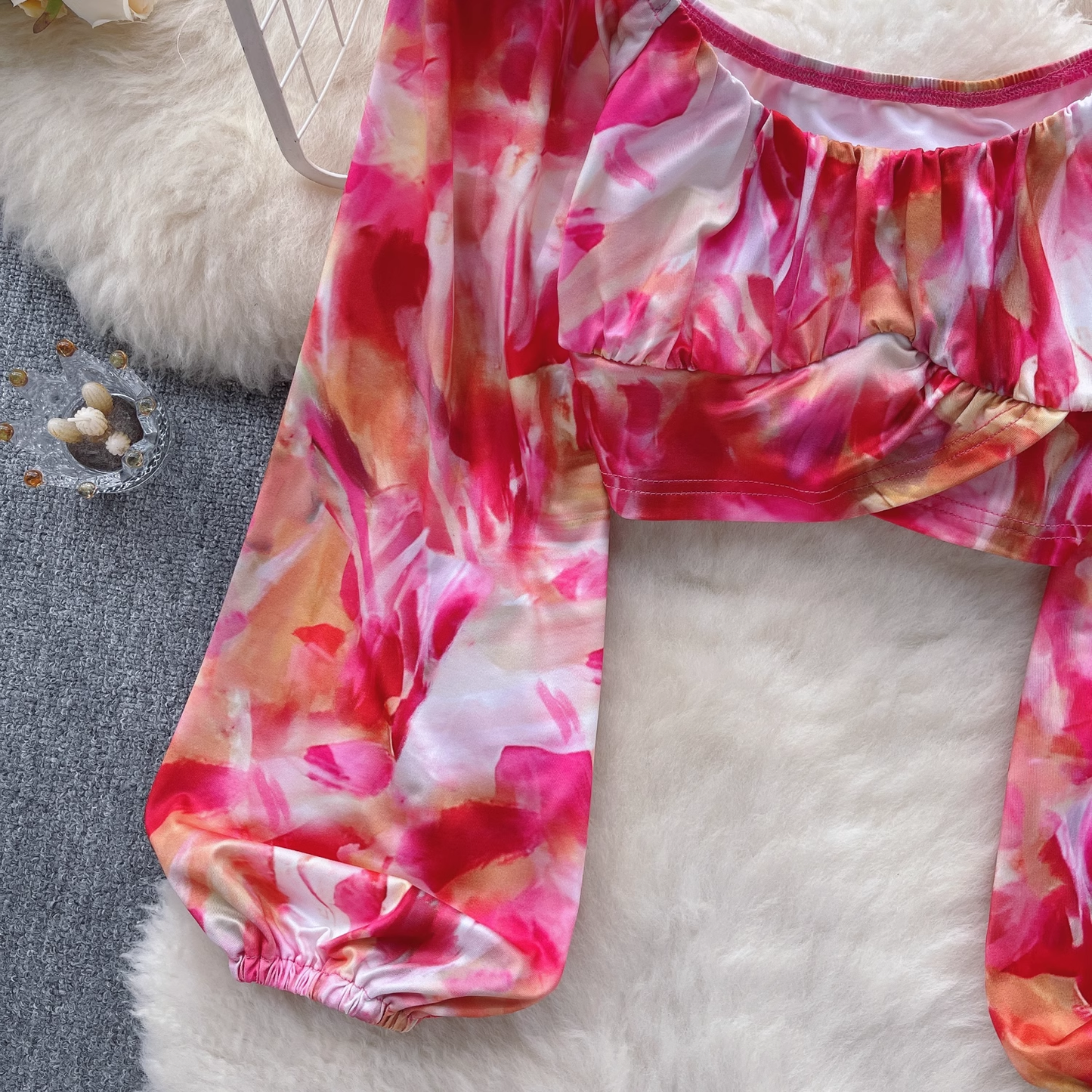 A cropped tie-dye print top with a ruched bust and long, flowing sleeves.