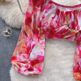 A cropped tie-dye print top with a ruched bust and long, flowing sleeves.