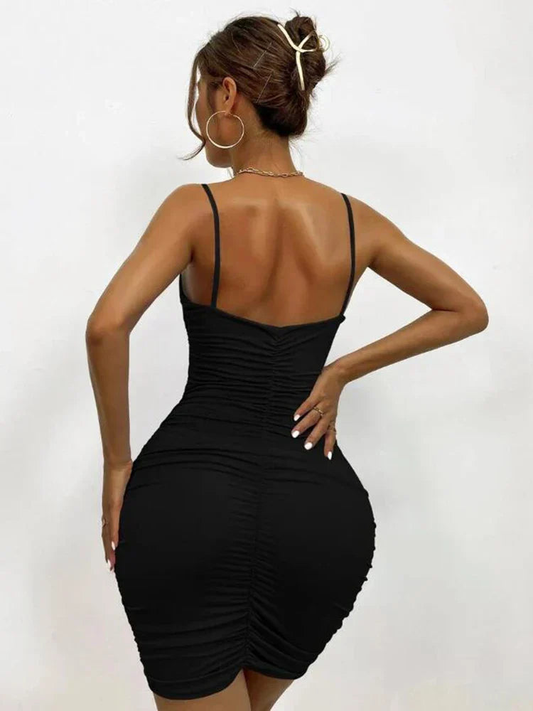 Back view of a woman in a black ruched bodycon dress with spaghetti straps.