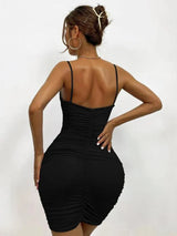 Back view of a woman in a black ruched bodycon dress with spaghetti straps.