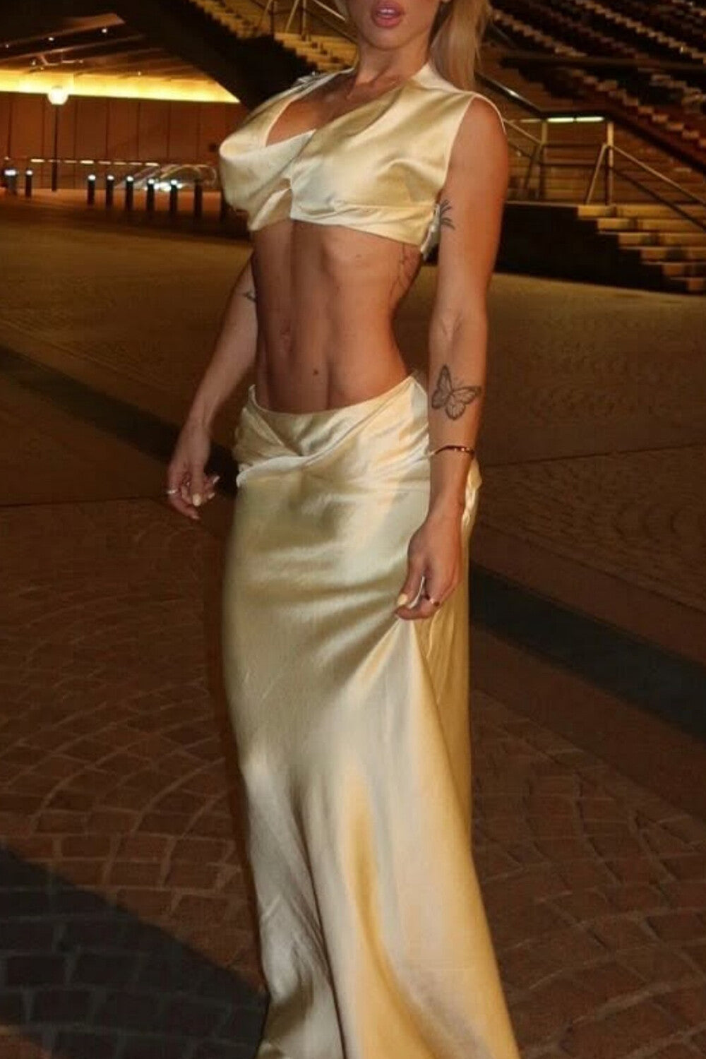 Full body shot of a woman in a beige satin evening gown.
