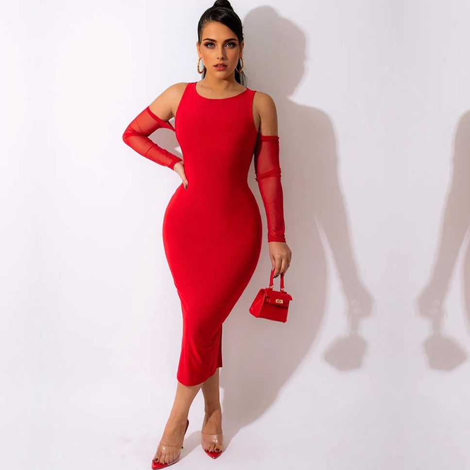 A woman in a red midi dress with sheer sleeves and a side slit, holding a small red purse.