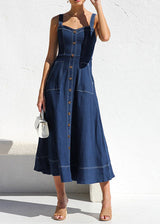 Woman holding a small white handbag while wearing a dark blue denim midi dress with a sweetheart neckline and button-down front.