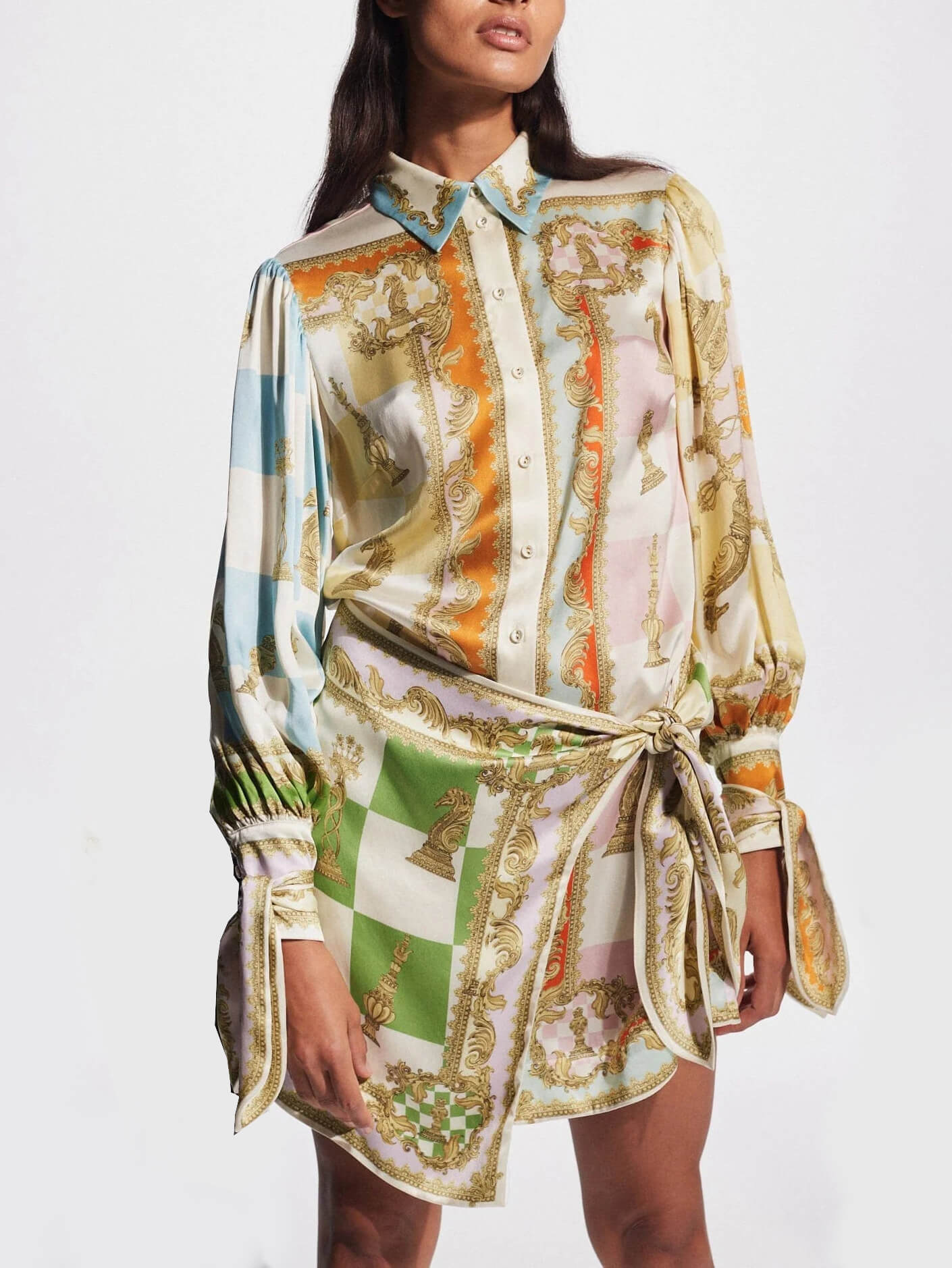 woman wearing a white, green, orange, blue, pink, and yellow patterned silk shirt dress with a tie waist and puffed sleeves
