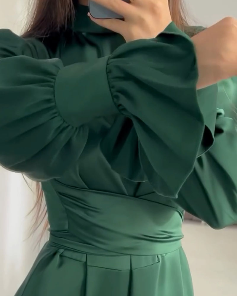 Detailed view of the ruffled cuffs and sleeves of the emerald green satin dress.