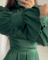 Detailed view of the ruffled cuffs and sleeves of the emerald green satin dress.