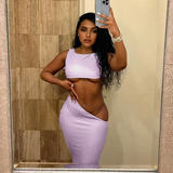 Woman in a lilac two-piece set with a cropped top and a high-waisted, ruched skirt with a side cut-out.