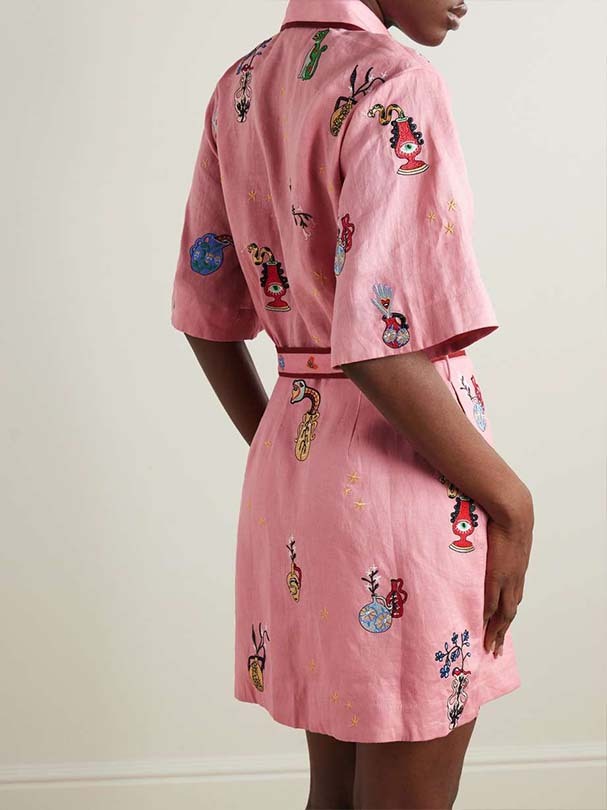Back view of a woman in a pink embroidered shirt dress.