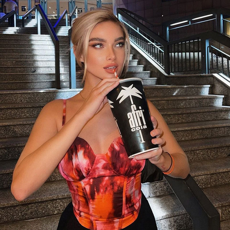 Woman drinking from a large cup while wearing a tie-dye top