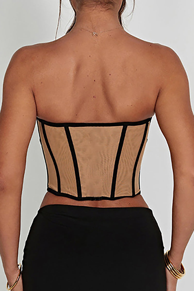 Back view of a woman wearing a tan mesh corset with black trim.