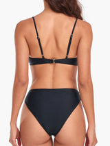 back view of a woman in a black bikini showing the strap detail and high-waisted bottoms