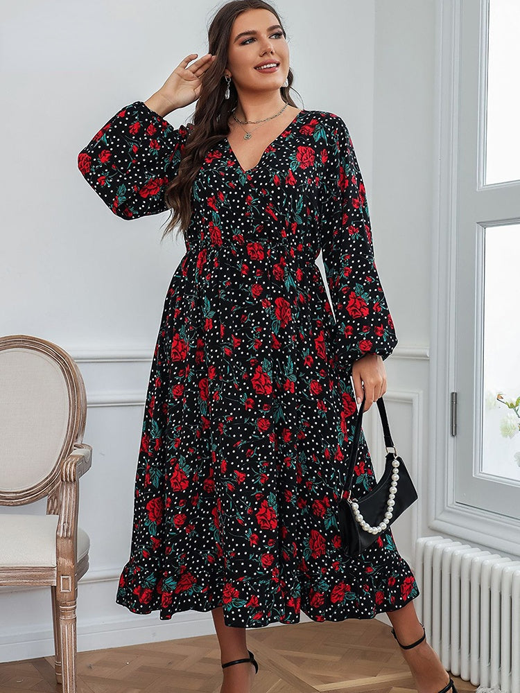 A plus-size woman posing with a black beaded handbag, wearing a black floral and polka dot midi dress.