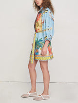 Side view of a woman wearing a colorful printed shirt dress with puff sleeves and a belted waist.