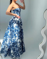 Woman taking a mirror selfie in a strapless blue and white floral print ball gown.