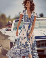 Woman in a blue and white floral maxi dress standing next to a vintage car.