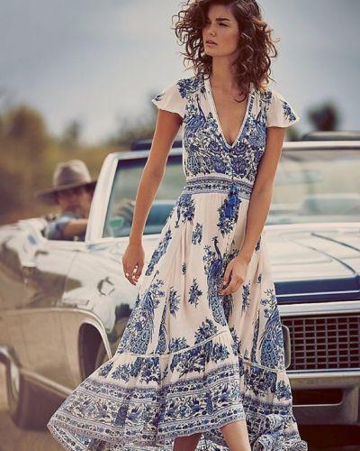 Woman in a blue and white floral maxi dress standing next to a vintage car.