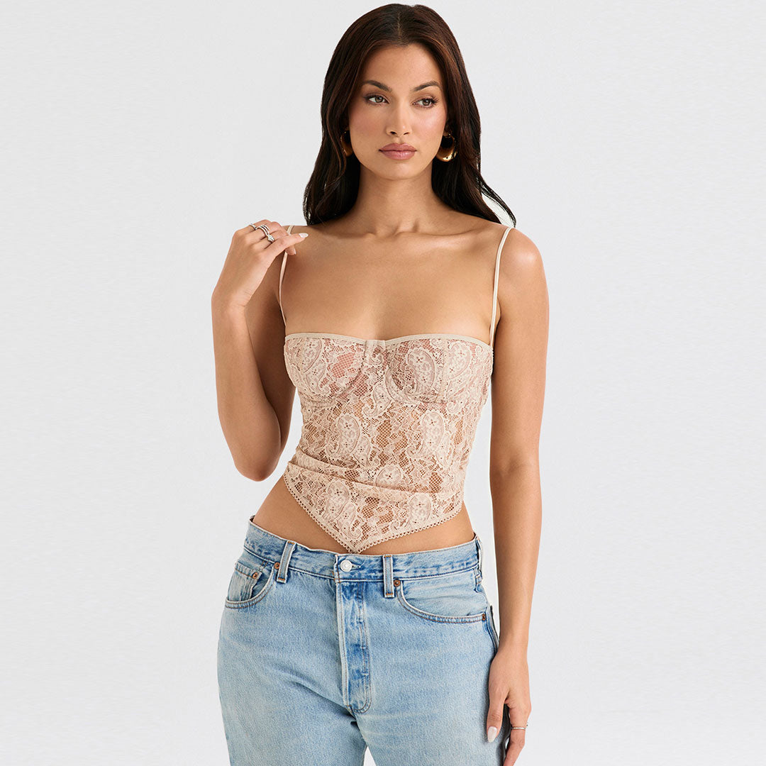 Woman wearing a beige lace corset top with light wash jeans, holding her shoulder strap