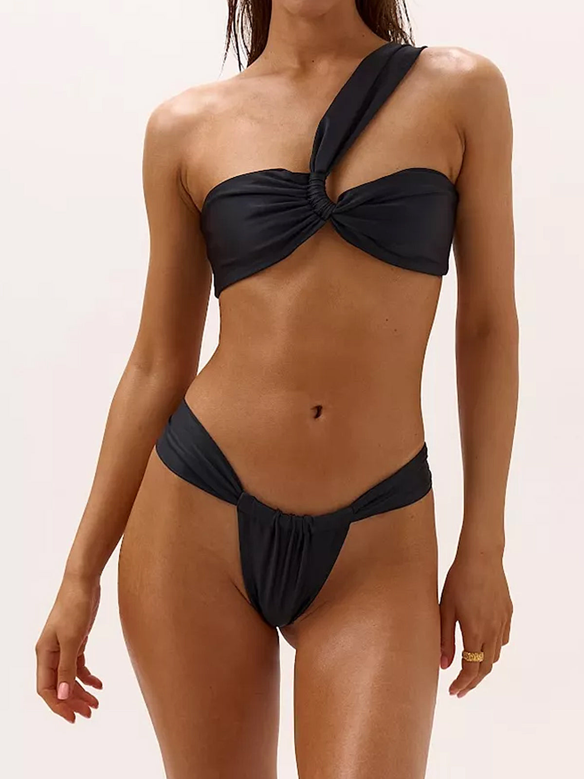 A woman models a black one-shoulder bikini with a twisted knot bust and high-cut bottoms.