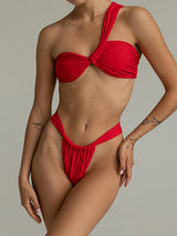 A woman models a red one-shoulder bikini with a twisted knot bust and high-cut bottoms.