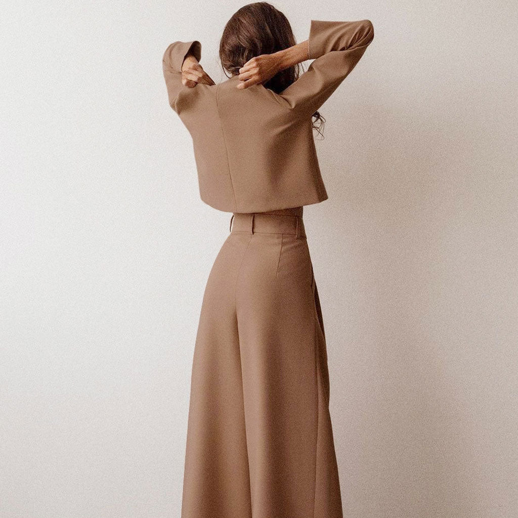 Back view of a woman in a tan two-piece set with wide-leg pants.