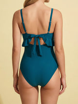Back view of a woman in a teal one-piece swimsuit with a bow tie closure