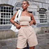 A woman poses outdoors in a beige crop top and matching shorts.