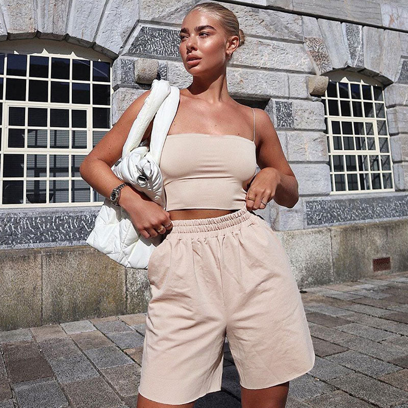 A woman poses outdoors in a beige crop top and matching shorts.