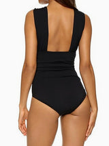 Back view of a woman wearing a black one-piece swimsuit with a deep V-back and ruched waist