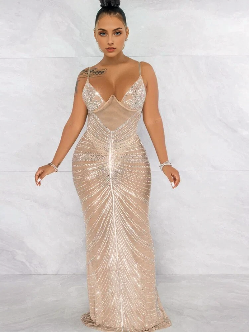 Woman in a sheer nude, floor-length gown with intricate silver beading arranged in vertical lines and intricate patterns on the bodice.