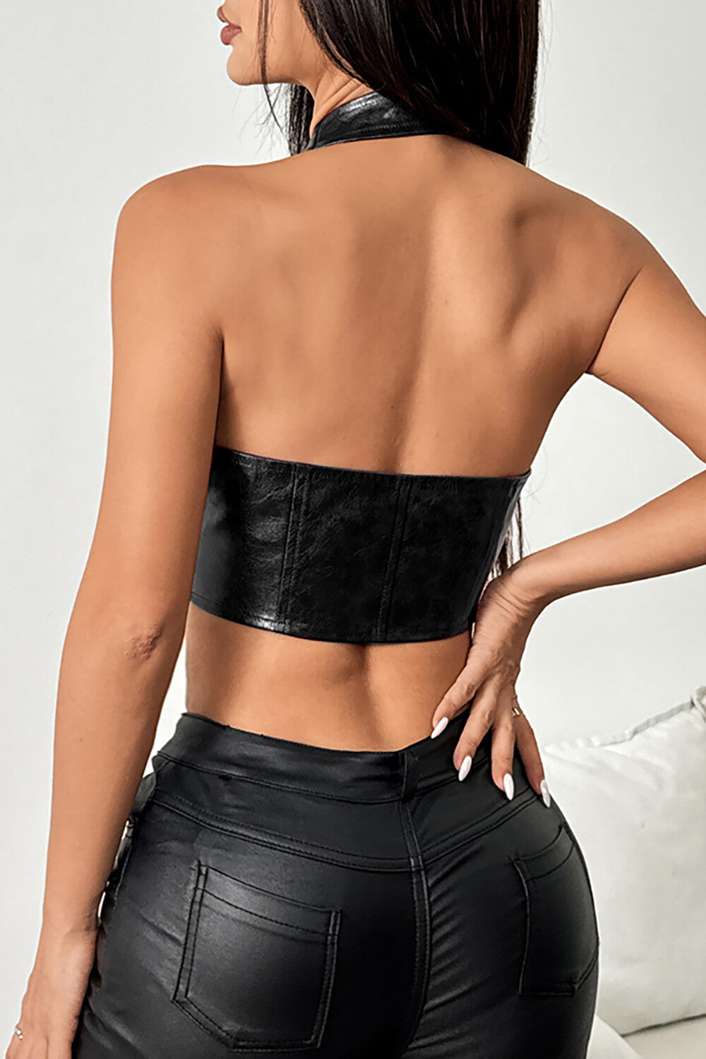 Back view of a woman wearing a black faux leather halter top