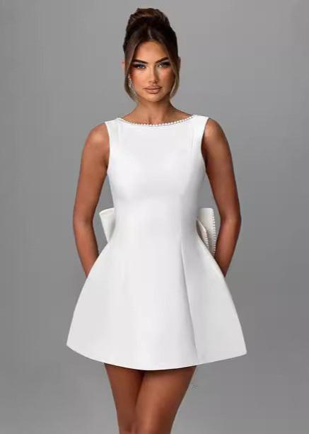 woman wearing a short white A-line dress with a bow detail