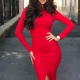 Woman in a red long-sleeved midi dress with a high slit, posing with hands on hips.
