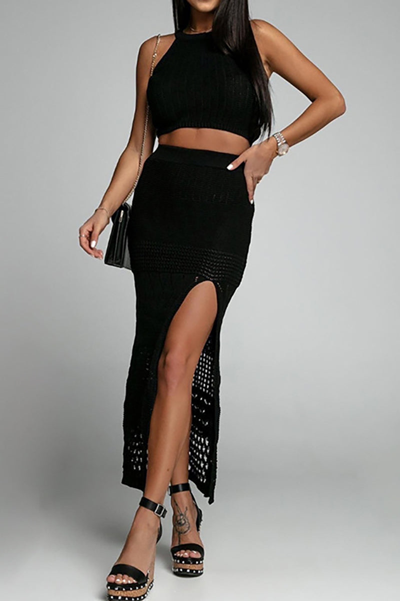 woman in black crochet crop top and skirt with high slit and studded heels