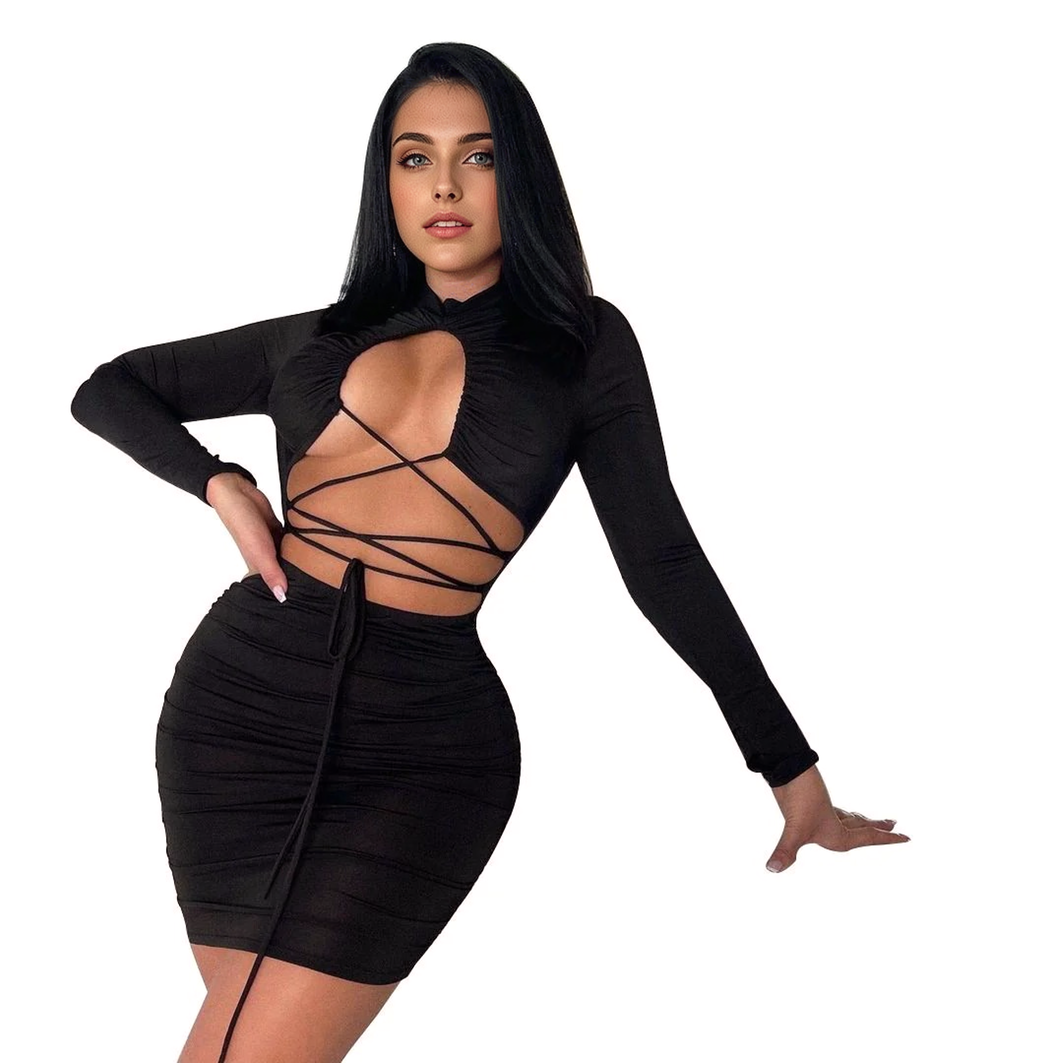 Woman in a black long-sleeved, cut-out, lace-up, ruched mini dress against a white background.