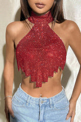 A woman wearing a vibrant red halter top with a fringe hem, paired with light-wash jeans.