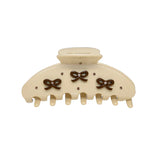 Close-up of a cream hair clip adorned with dark brown bows and sparkling embellishments.