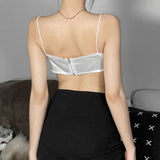 Back view of a woman wearing a white satin crop top with spaghetti straps and a zipper