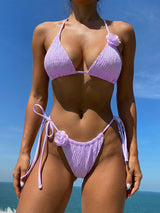 Woman wearing a lavender ruched bikini with rose applique