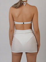 back view of a woman wearing a white halter bikini top and a white mini skirt