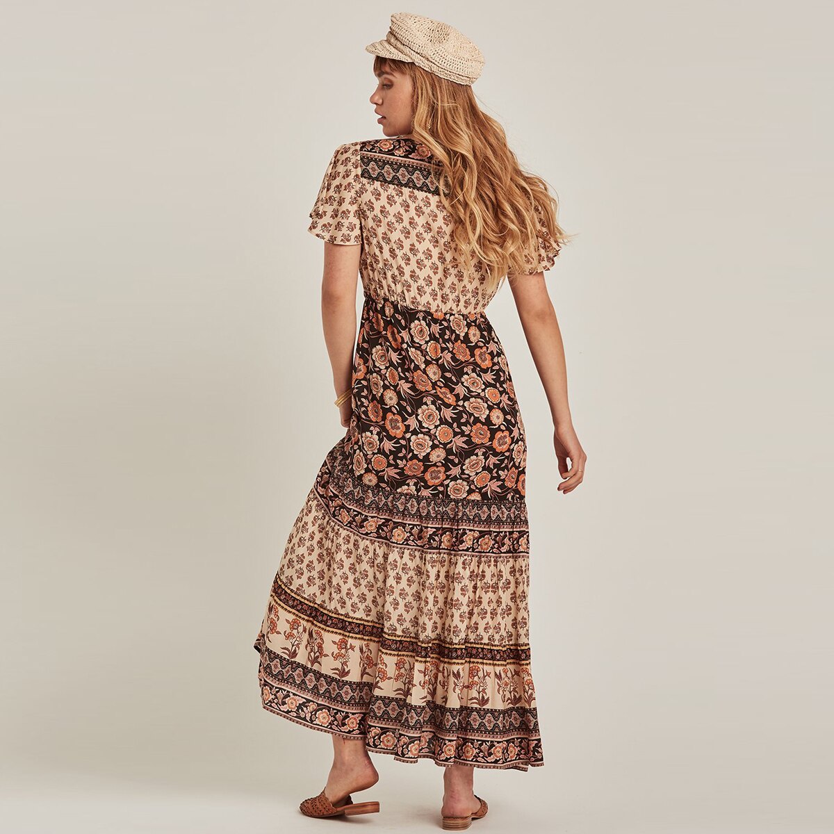 back view of a woman wearing a floral print maxi dress and a straw hat