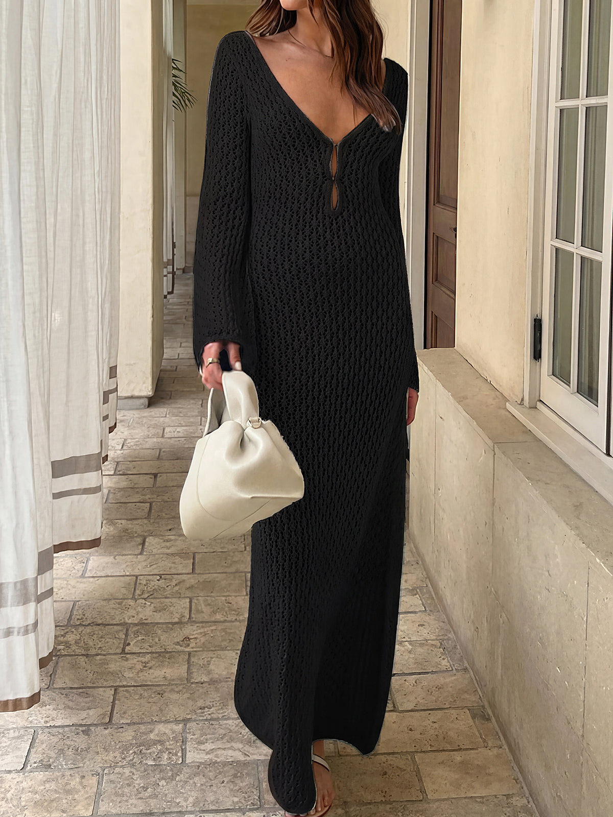 Woman wearing a black crochet knit maxi dress with bell sleeves and a deep V-neck.