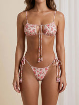 A woman wearing a pink floral print bikini with tassel details.