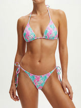 Woman wearing a pink and teal shell print halter neck bikini top and matching tie-side bikini bottoms from the front.
