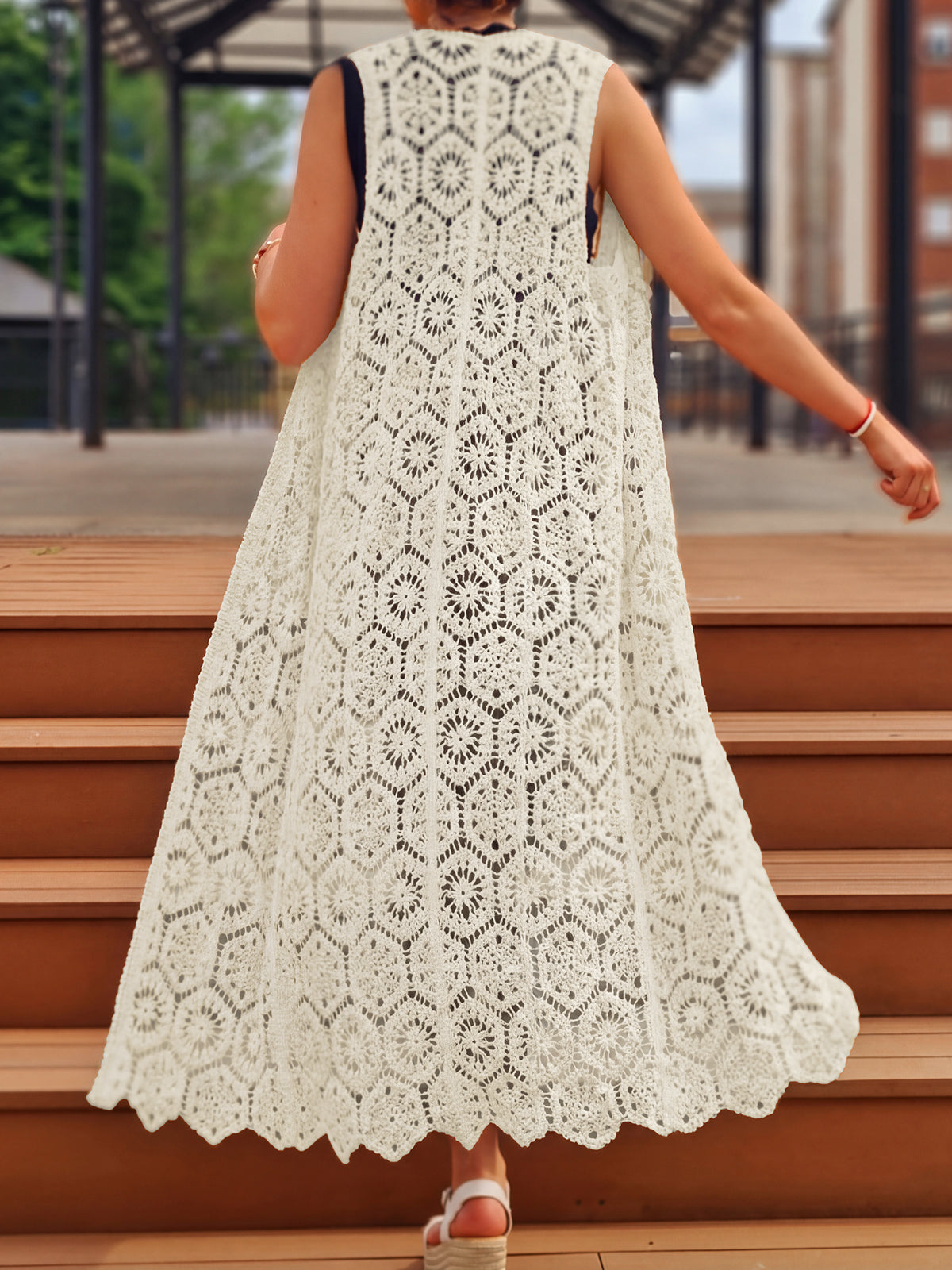 Back view of a woman wearing a long white crochet vest