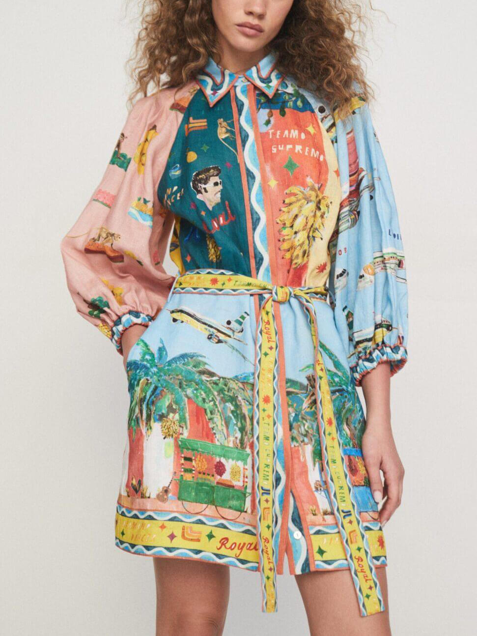 Front view of a woman wearing a colorful printed shirt dress with puff sleeves and a belted waist.