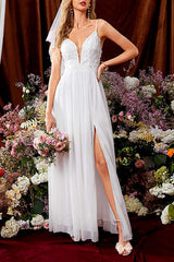 Woman in a white wedding dress with a high slit and floral applique on the bodice, holding a bouquet of pink roses.