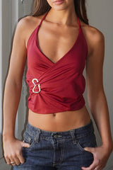 woman wearing a red halter neck wrap top with a silver ring detail and blue denim jeans