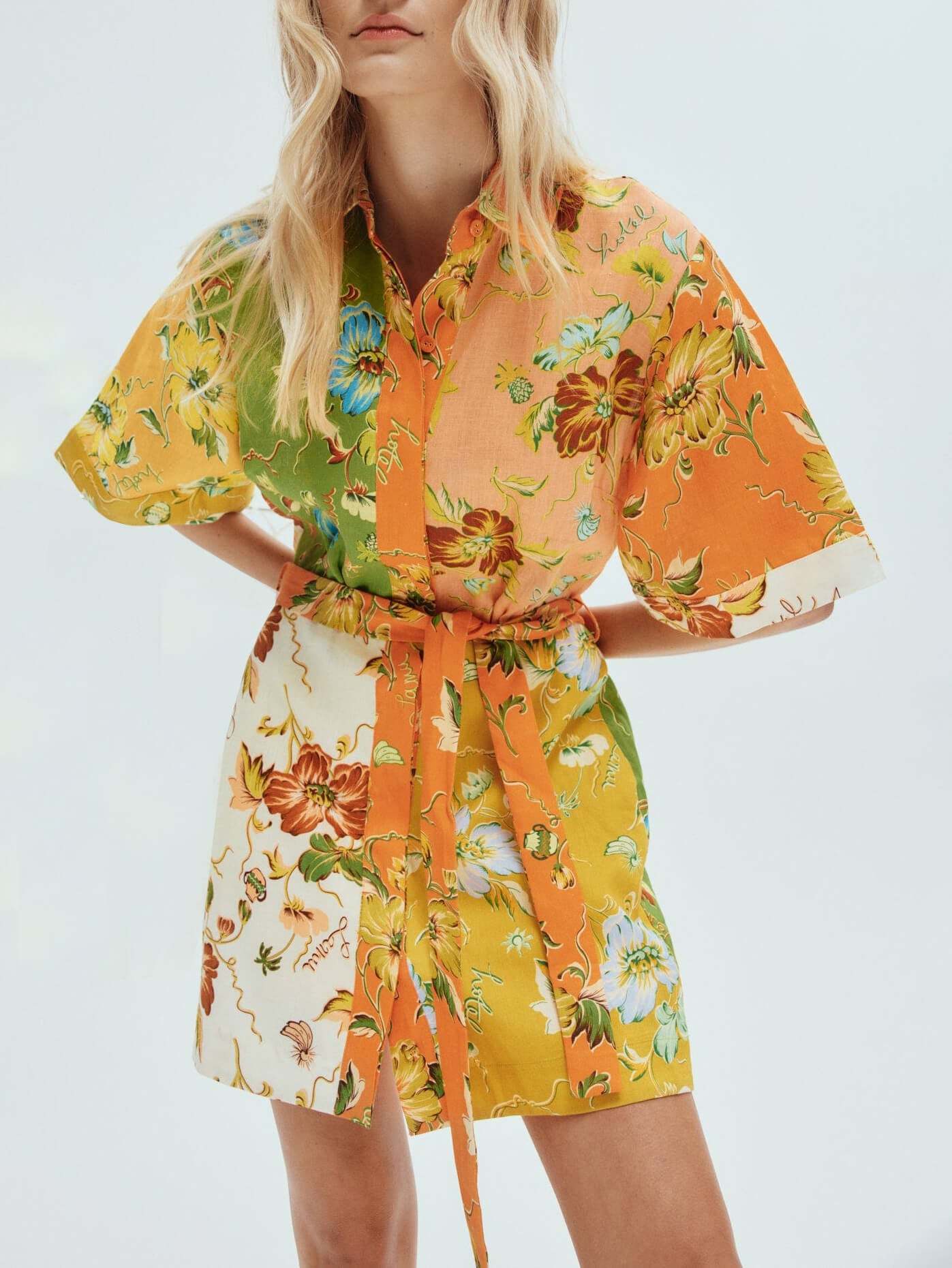 Front view of a woman in a colorful floral print shirt dress with a belted waist.